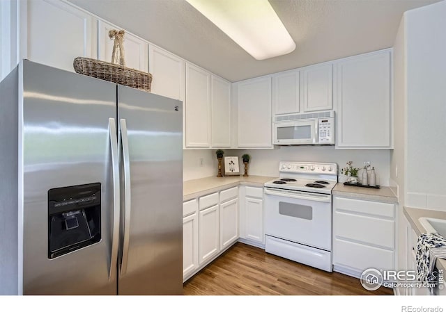 kitchen featuring white appliances, white cabinetry, and light wood-type flooring