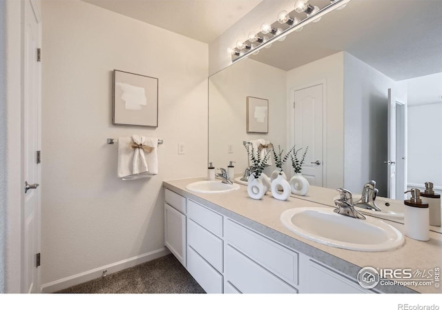 full bath featuring double vanity and baseboards