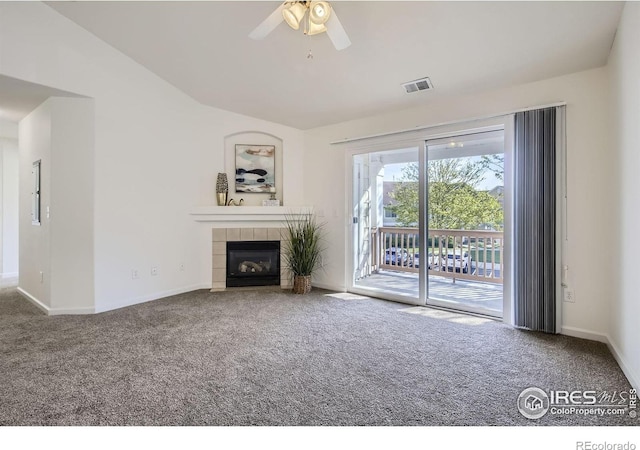 unfurnished living room featuring carpet, a ceiling fan, lofted ceiling, baseboards, and a tile fireplace