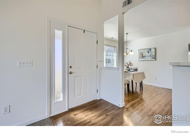 entryway featuring wood finished floors, baseboards, and a textured ceiling