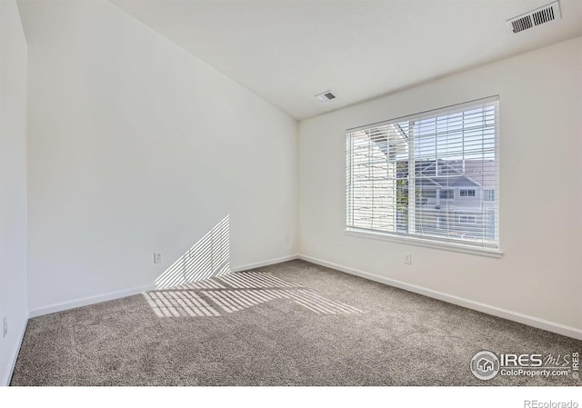 carpeted spare room with baseboards and vaulted ceiling