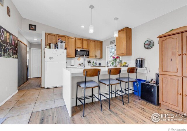3100 Denton Ave, Boulder, CO 80303 - kitchen featuring stainless steel microwave, freestanding refrigerator, vaulted ceiling, a peninsula, and light wood finished floors