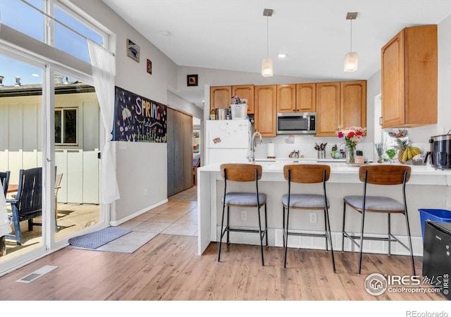 3100 Denton Ave, Boulder, CO 80303 - kitchen with stainless steel microwave, freestanding refrigerator, lofted ceiling, light wood-style floors, and pendant lighting