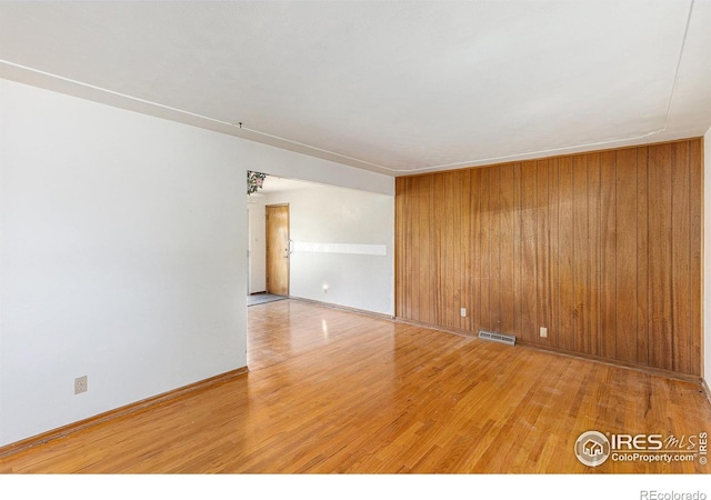 1207 S Tyler Ave, Loveland, CO 80537 - unfurnished room with light wood finished floors, wooden walls, and baseboards