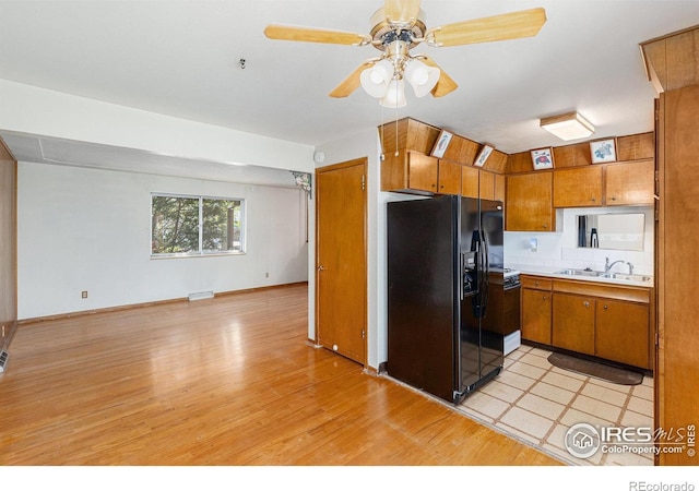 1207 S Tyler Ave, Loveland, CO 80537 - kitchen with black fridge, brown cabinets, light wood-style floors, light countertops, and a sink