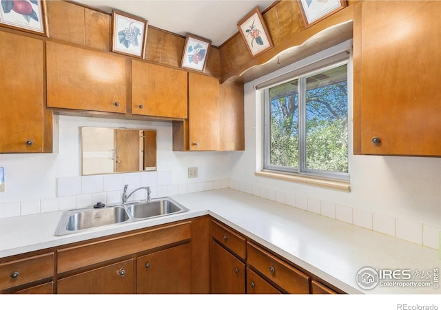 1207 S Tyler Ave, Loveland, CO 80537 - kitchen with a sink, light countertops, brown cabinetry, and decorative backsplash