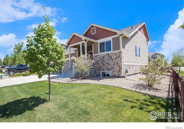 view of front of house featuring stone siding, a porch, a front yard, and concrete driveway