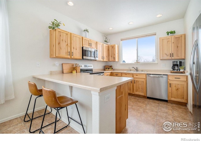 kitchen with stainless steel appliances, a sink, light brown cabinets, and recessed lighting