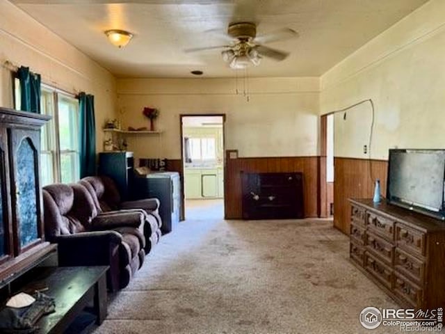 230 W Chase St, Haxtun, CO 80731 - living room with healthy amount of natural light, wainscoting, ceiling fan, wooden walls, and carpet flooring