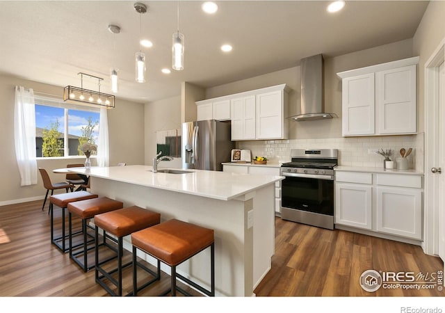 3751 Beech Tree St, Wellington, CO 80549 - kitchen featuring stainless steel appliances, wall chimney range hood, a sink, backsplash, and dark wood finished floors