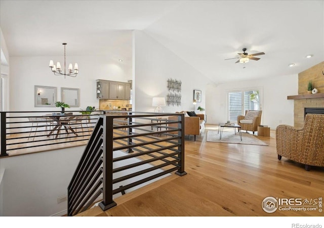7726 Kit Fox Dr, Wellington, CO 80549 - stairs featuring lofted ceiling, wood finished floors, a ceiling fan, a chandelier, and a stone fireplace