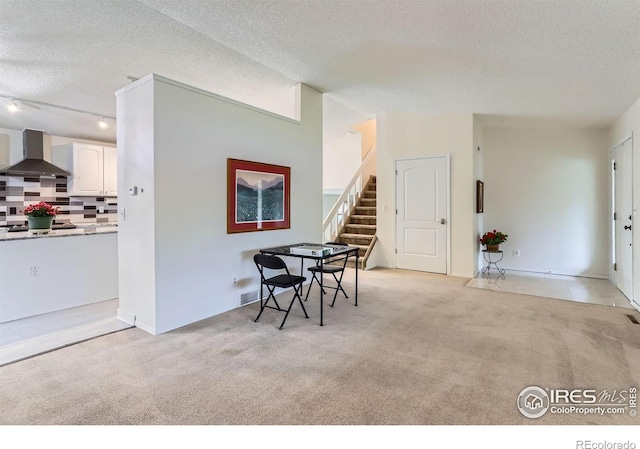 dining space with a textured ceiling, stairway, and light colored carpet