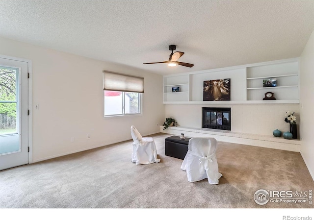 living area with carpet flooring, healthy amount of natural light, a textured ceiling, ceiling fan, and baseboards