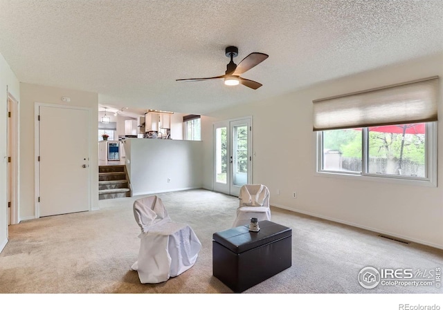 carpeted living area featuring a textured ceiling, ceiling fan, stairs, and baseboards