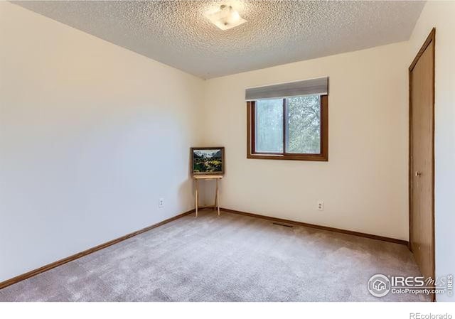 unfurnished room featuring carpet flooring, a textured ceiling, and baseboards
