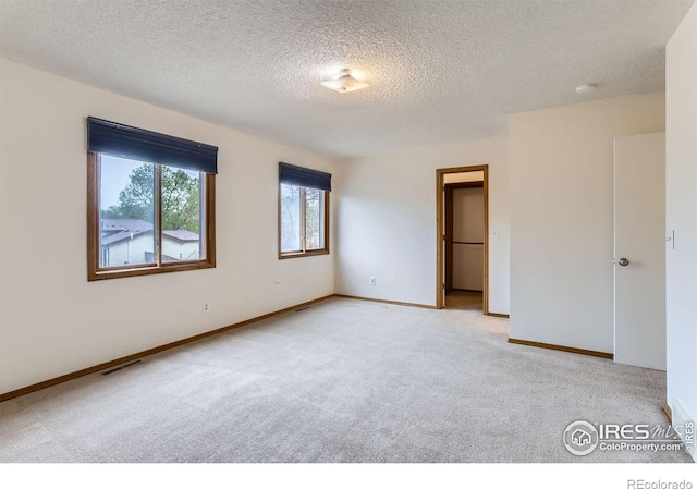 unfurnished bedroom with light carpet, a textured ceiling, and baseboards