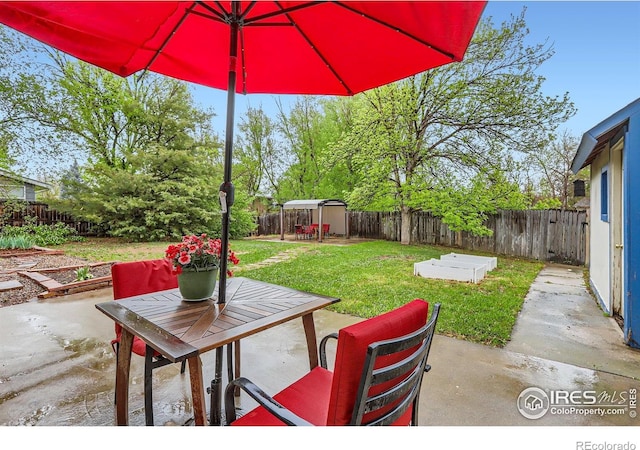 view of patio / terrace with a storage unit, outdoor dining area, and an outdoor structure