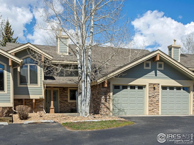 865 Crabapple Ln, Estes Park, CO 80517 - view of front of home featuring asphalt driveway, stone siding, a chimney, a garage, and roof with shingles