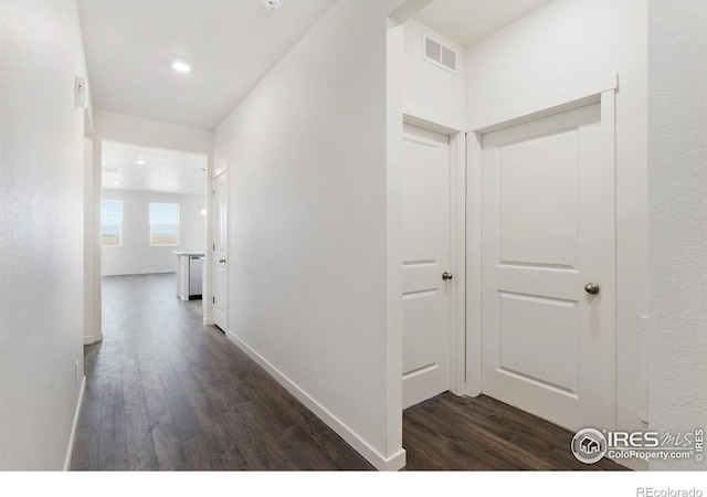 hall featuring dark wood-style flooring, recessed lighting, and baseboards