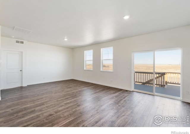 empty room featuring dark wood-style floors, baseboards, and recessed lighting