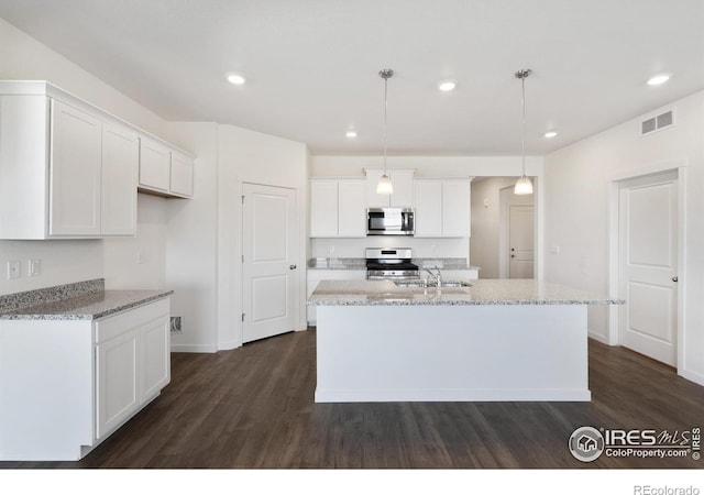 kitchen with appliances with stainless steel finishes, a sink, dark wood-type flooring, white cabinetry, and a kitchen island with sink