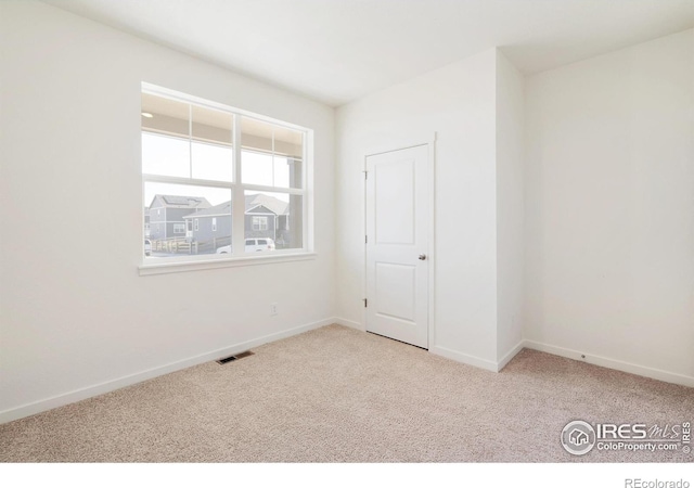 spare room featuring carpet floors and baseboards