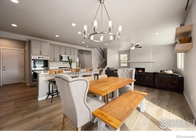 4532 Big Horn Pkwy, Johnstown, CO 80534 - dining space featuring ceiling fan, a tile fireplace, stairway, light wood finished floors, and recessed lighting