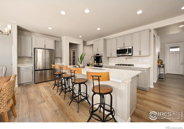 4532 Big Horn Pkwy, Johnstown, CO 80534 - kitchen with stainless steel appliances, light wood-type flooring, light countertops, a kitchen bar, and recessed lighting