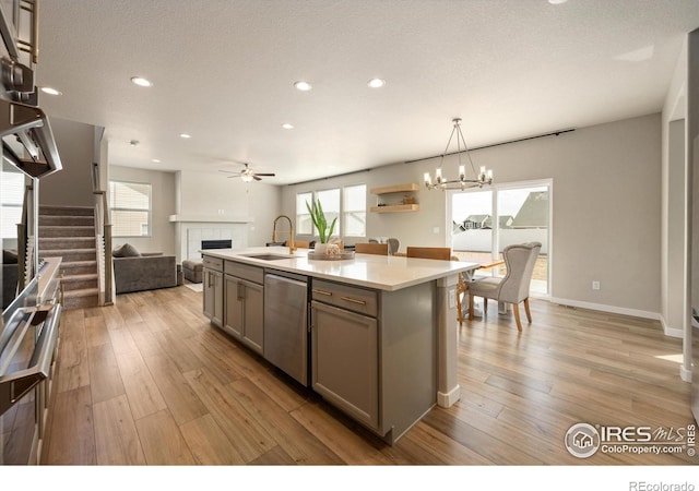 4532 Big Horn Pkwy, Johnstown, CO 80534 - kitchen with a sink, stainless steel dishwasher, a tile fireplace, gray cabinetry, and open floor plan