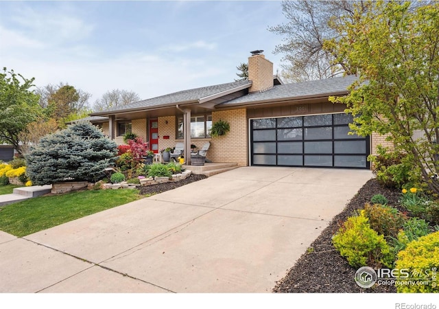 2001 James Dr, Loveland, CO 80538 - view of front facade featuring an attached garage, brick siding, driveway, and a chimney