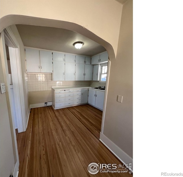 1219 16th St, Greeley, CO 80631 - kitchen with arched walkways, dark wood-type flooring, white cabinets, light countertops, and decorative backsplash