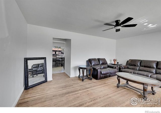 living area featuring light wood finished floors, a ceiling fan, and baseboards