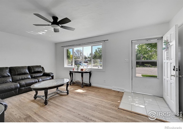 living area with healthy amount of natural light, light wood-style floors, a ceiling fan, and baseboards