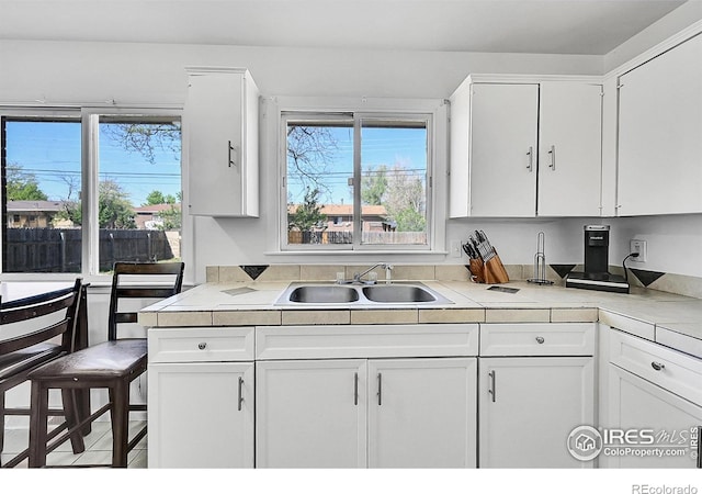 kitchen with a sink, white cabinets, and healthy amount of natural light