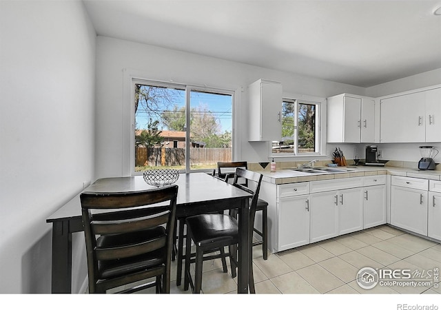 kitchen featuring a sink, light tile patterned floors, and white cabinets