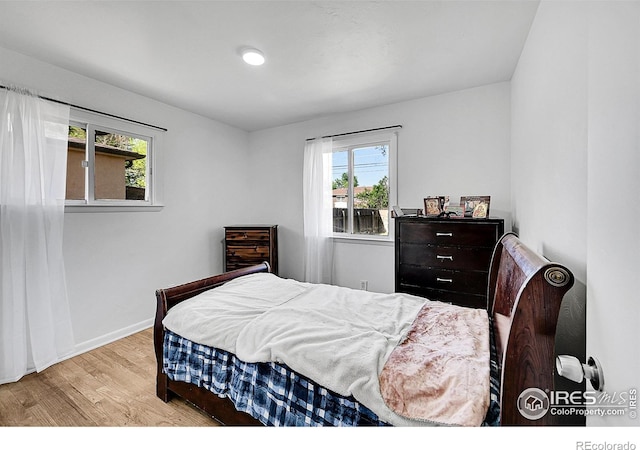 bedroom with wood finished floors, multiple windows, and baseboards