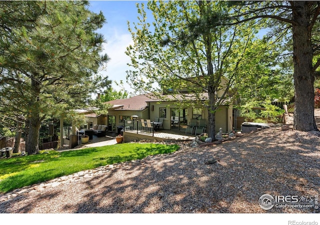 back of property with stucco siding, a deck, and a yard