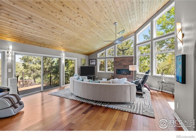 living area with high vaulted ceiling, wood-type flooring, wooden ceiling, a ceiling fan, and a glass covered fireplace