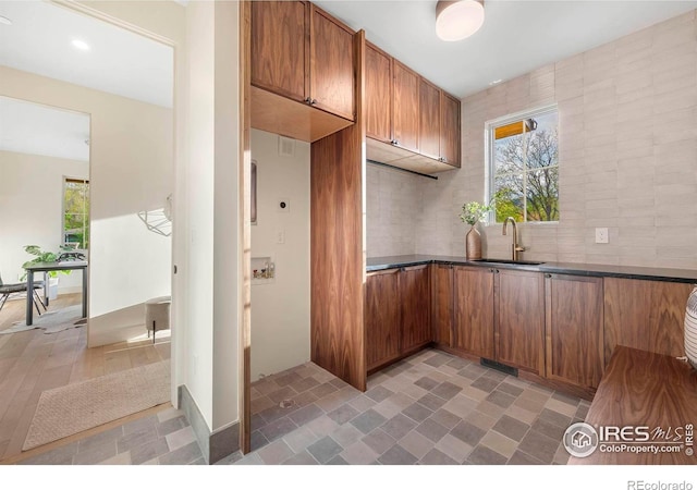kitchen with a sink, healthy amount of natural light, dark countertops, and brown cabinets