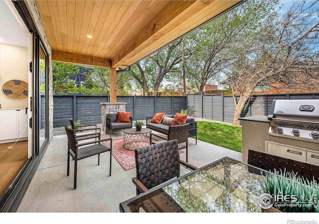 view of patio / terrace featuring a grill, a fenced backyard, an outdoor living space, and an outdoor kitchen