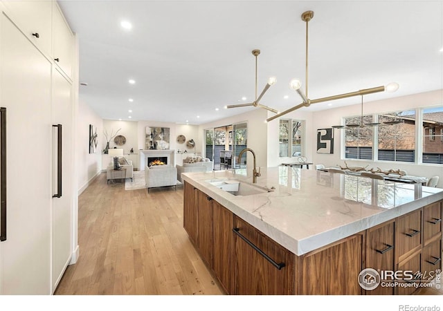 kitchen featuring a sink, open floor plan, brown cabinets, and recessed lighting