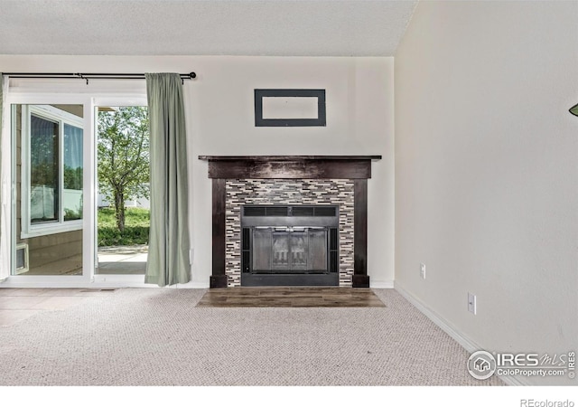 unfurnished living room featuring a tile fireplace, carpet floors, baseboards, and a textured ceiling