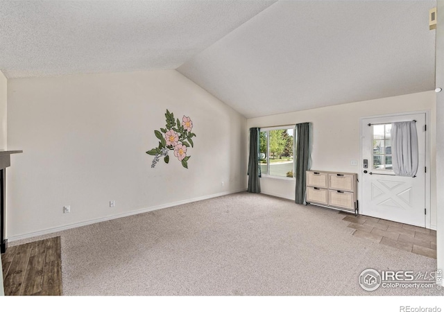 unfurnished living room with carpet, lofted ceiling, and baseboards