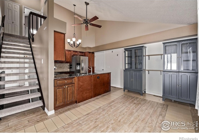 kitchen featuring stainless steel fridge with ice dispenser, vaulted ceiling, a ceiling fan, light wood-style flooring, and dark stone countertops