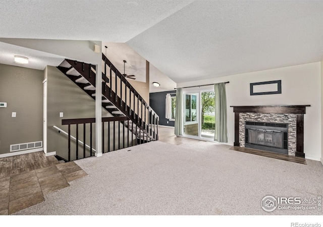 unfurnished living room with vaulted ceiling, a textured ceiling, carpet, a tiled fireplace, and baseboards