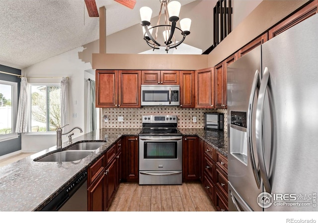 kitchen featuring appliances with stainless steel finishes, a sink, a chandelier, tasteful backsplash, and light wood-style flooring