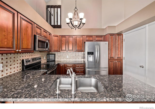 kitchen featuring stainless steel appliances, a sink, a chandelier, decorative backsplash, and high vaulted ceiling