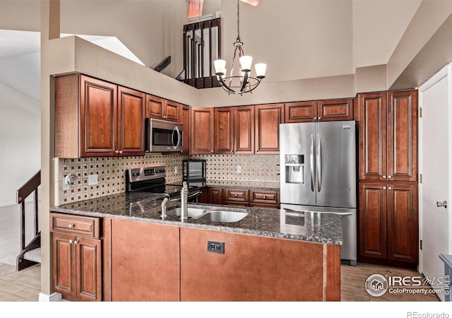 kitchen with stainless steel appliances, a chandelier, a peninsula, dark stone counters, and backsplash