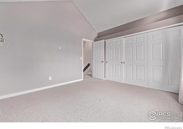 unfurnished bedroom with carpet flooring, vaulted ceiling, a closet, and baseboards