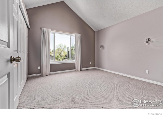 carpeted empty room featuring vaulted ceiling, baseboards, and a textured ceiling